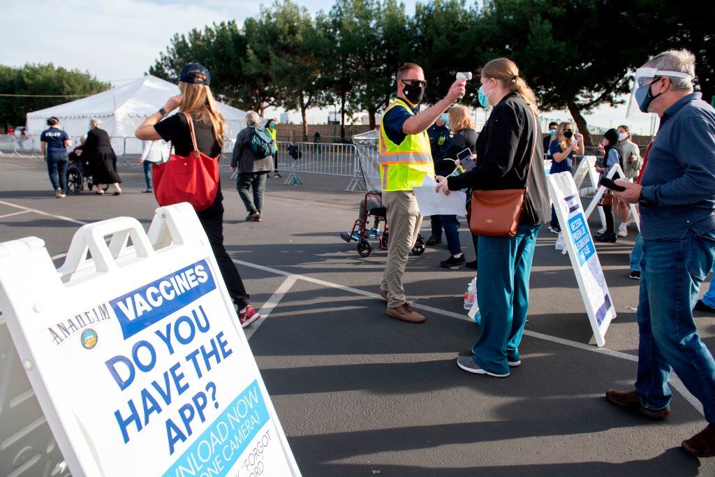 People have their temperature checked as they arrive at a Disneyland parking lot to receive Covid-19 vaccines on the opening day of the Disneyland Covid-19 vaccination "super Point-of-Dispensing" (POD) site, January 13, 2021, in Anaheim, California. - California's Disneyland opened a giant coronavirus vaccination center on January 13, some 10 months after the pandemic's appearance forced the closure of the world-famous theme park. The first few hundred patients lucky enough to bag online appointments drove up to the Anaheim resort's parking lot Wednesday morning, where those over 65 and health care workers are being inoculated in white tents. (Photo by VALERIE MACON / AFP) (Photo by VALERIE MACON/AFP via Getty Images)