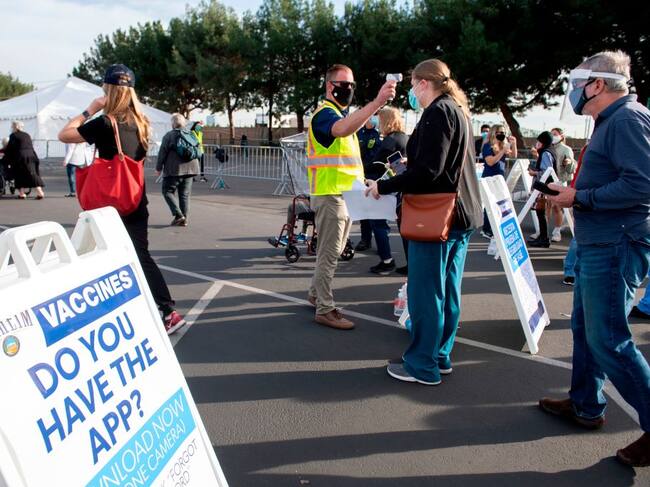People have their temperature checked as they arrive at a Disneyland parking lot to receive Covid-19 vaccines on the opening day of the Disneyland Covid-19 vaccination "super Point-of-Dispensing" (POD) site, January 13, 2021, in Anaheim, California. - California's Disneyland opened a giant coronavirus vaccination center on January 13, some 10 months after the pandemic's appearance forced the closure of the world-famous theme park. The first few hundred patients lucky enough to bag online appointments drove up to the Anaheim resort's parking lot Wednesday morning, where those over 65 and health care workers are being inoculated in white tents. (Photo by VALERIE MACON / AFP) (Photo by VALERIE MACON/AFP via Getty Images)
