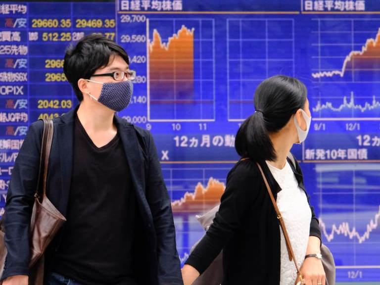 Personas observan los resultados de las bolsas de valores en Tokio