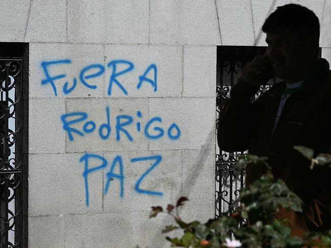 A man walks past a graffiti reading "Rodrigo Paz out," referring to Bolivia's President in La Paz, on May 19, 2026, the day after a protest in demand of his resignation. Bolivian protests calling for center-right President Rodrigo Paz to resign intensified on May 18, 2026 as demonstrators swarmed government buildings and a protest leader faced terrorism charges over the unrest. Riot police clashed with protesters for hours, tear gas shrouded the streets of La Paz, shops were shuttered and supplies ran low due to protest blockades choking routes into the capital city. (Photo by AIZAR RALDES / AFP via Getty Images)