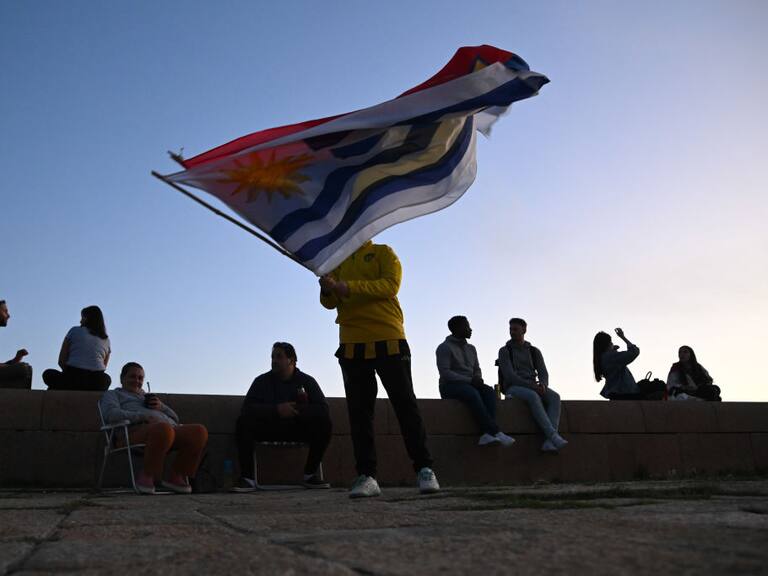 Una persona con la bandera de Uruguay en la zona de la Rambla en la ciudad de Montevideo