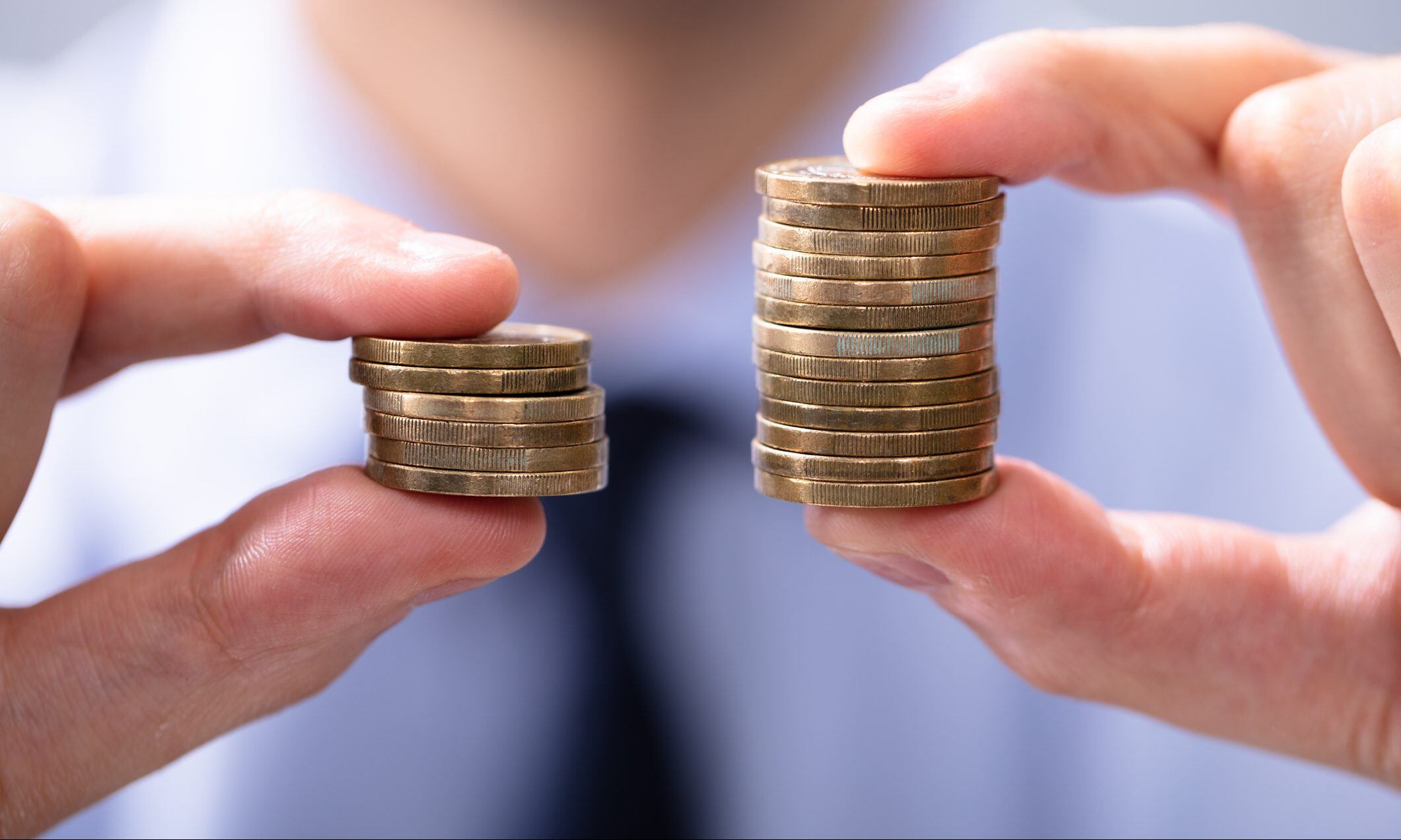 Man Holding Two Coin Stacks To Compare
