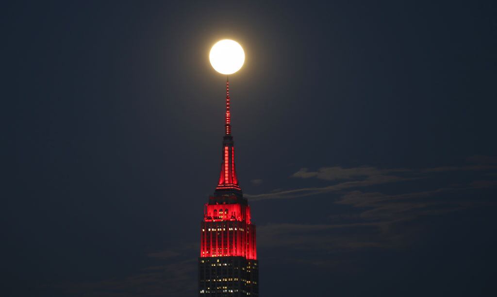 UNION CITY, NJ - APRIL 7: The Super Pink Moon rises behind the Empire State in New York City lit to honor COVID-19 healthworkers on April 7, 2020 as seen from Union City, New Jersey.   (Photo by Gary Hershorn/Getty Images)