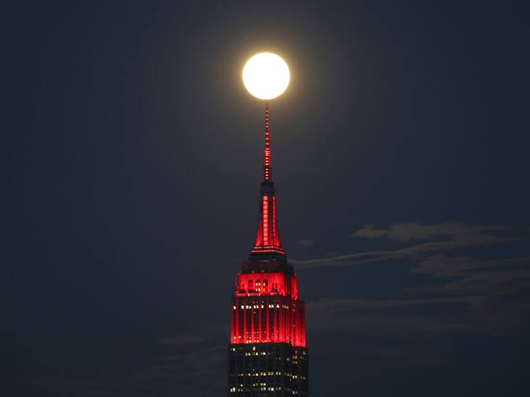 UNION CITY, NJ - APRIL 7: The Super Pink Moon rises behind the Empire State in New York City lit to honor COVID-19 healthworkers on April 7, 2020 as seen from Union City, New Jersey.   (Photo by Gary Hershorn/Getty Images)