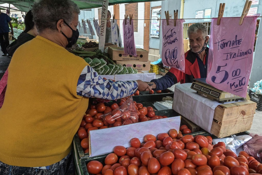 Una mujer compra en una feria de verduras en Brasil
