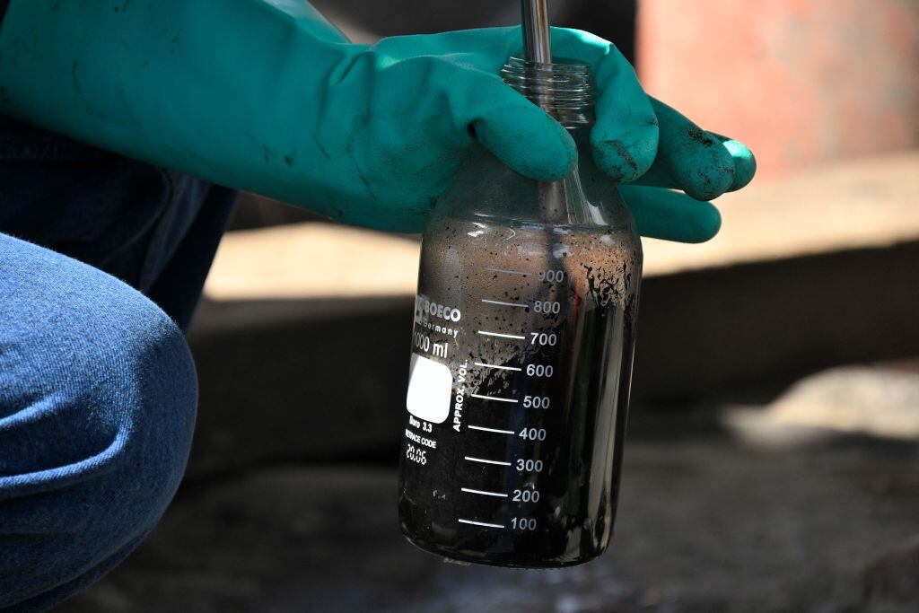 Un técnico de la empresa estatal Petroecuador reúne crudo desde una tubería en un sector del Amazonas en Ecuador.