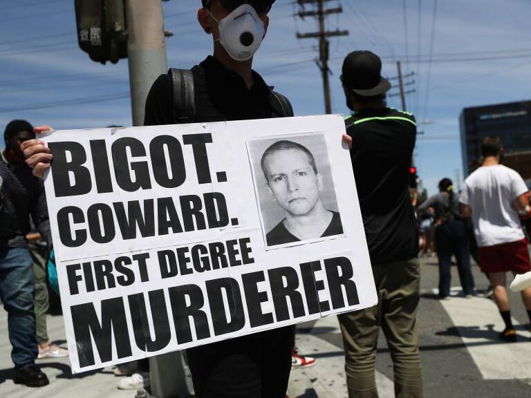 LOS ANGELES, CALIFORNIA - MAY 30: A protester holds a sign with a photo of former Minneapolis police officer Derek Chauvin during demonstrations following the death of George Floyd on May 30, 2020 in Los Angeles, California. Chauvin was taken into custody for Floyd&#039;s death. Chauvin has been accused of kneeling on Floyd&#039;s neck as he pleaded with him about not being able to breathe. Floyd was pronounced dead a short while later. Chauvin and 3 other officers, who were involved in the arrest, were fired from the police department after a video of the arrest was circulated.  (Photo by Mario Tama/Getty Images)
