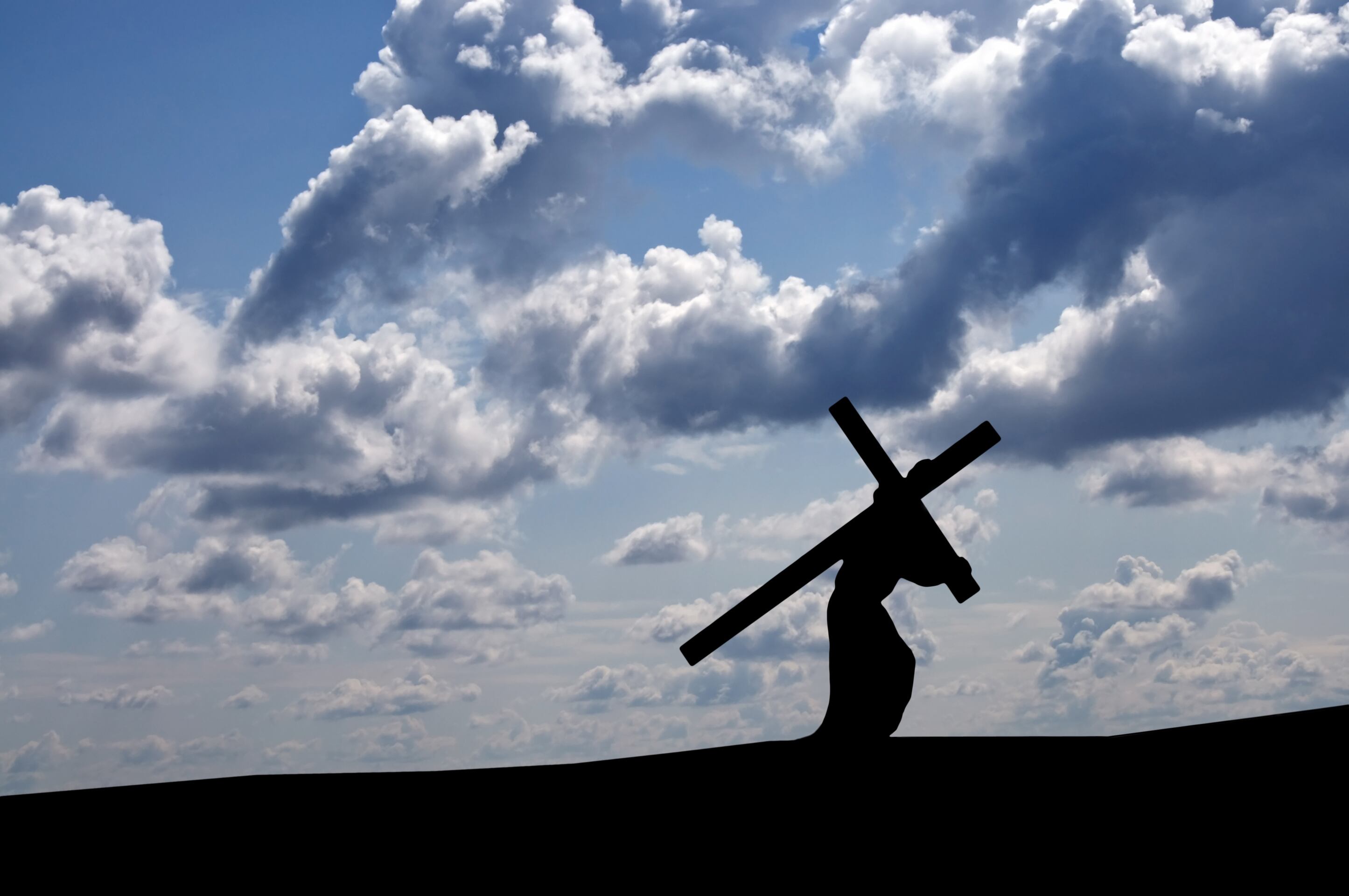 Against an black/blue and white sky, Jesus is carrying the Cross towrds calvary and his Crucifixion.