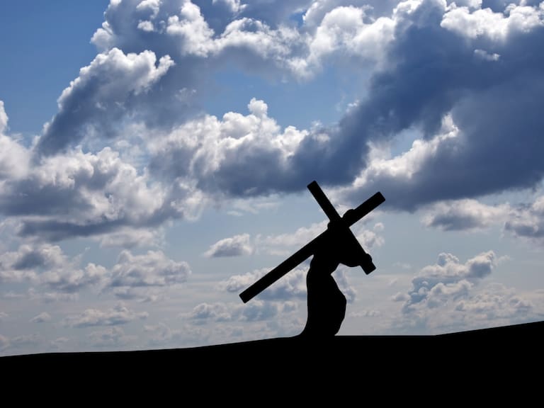 Against an black/blue and white sky, Jesus is carrying the Cross towrds calvary and his Crucifixion.