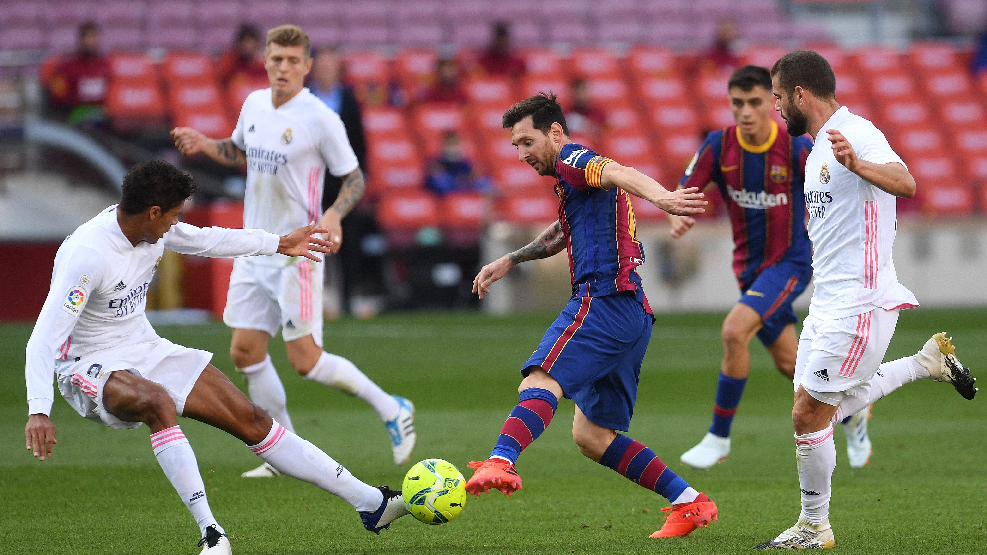 BARCELONA, SPAIN - OCTOBER 24: Lionel Messi of Barcelona controls the ball as Raphael Varane of Real Madrid and Luka Modric of Real Madrid look on during the La Liga Santander match between FC Barcelona and Real Madrid at Camp Nou on October 24, 2020 in Barcelona, Spain. Sporting stadiums around Spain remain under strict restrictions due to the Coronavirus Pandemic as Government social distancing laws prohibit fans inside venues resulting in games being played behind closed doors. (Photo by Alex Caparros/Getty Images)