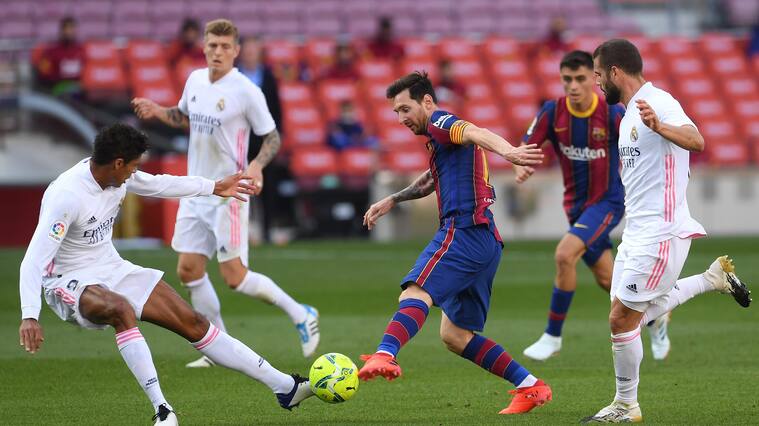 BARCELONA, SPAIN - OCTOBER 24: Lionel Messi of Barcelona controls the ball as Raphael Varane of Real Madrid and Luka Modric of Real Madrid look on during the La Liga Santander match between FC Barcelona and Real Madrid at Camp Nou on October 24, 2020 in Barcelona, Spain. Sporting stadiums around Spain remain under strict restrictions due to the Coronavirus Pandemic as Government social distancing laws prohibit fans inside venues resulting in games being played behind closed doors. (Photo by Alex Caparros/Getty Images)