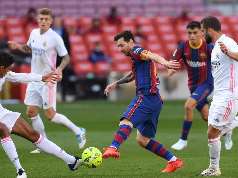 BARCELONA, SPAIN - OCTOBER 24: Lionel Messi of Barcelona controls the ball as Raphael Varane of Real Madrid and Luka Modric of Real Madrid look on during the La Liga Santander match between FC Barcelona and Real Madrid at Camp Nou on October 24, 2020 in Barcelona, Spain. Sporting stadiums around Spain remain under strict restrictions due to the Coronavirus Pandemic as Government social distancing laws prohibit fans inside venues resulting in games being played behind closed doors. (Photo by Alex Caparros/Getty Images)