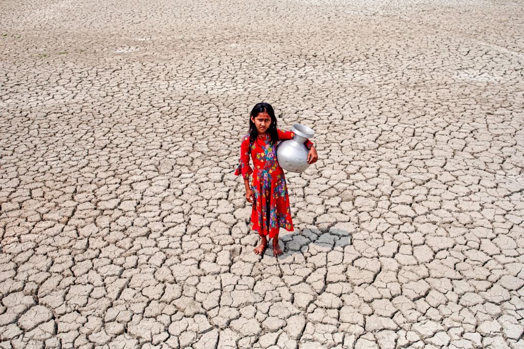 Una niña camina por un terreno seco buscando agua en Bangladesh