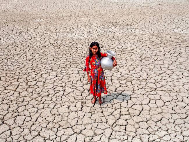 Una niña camina por un terreno seco buscando agua en Bangladesh