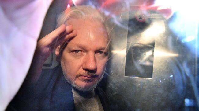 WikiLeaks founder Julian Assange gestures from the window of a prison van as he is driven out of Southwark Crown Court in London on May 1, 2019, after having been sentenced to 50 weeks in prison for breaching his bail conditions in 2012. - A British judge on Wednesday sentenced WikiLeaks founder Julian Assange to 50 weeks in prison for breaching his bail conditions in 2012. Assange took refuge in Ecuador's London embassy to avoid extradition to Sweden and was only arrested last month after Ecuador withdrew his asylum status. (Photo by Daniel LEAL / AFP) (Photo by DANIEL LEAL/AFP via Getty Images)