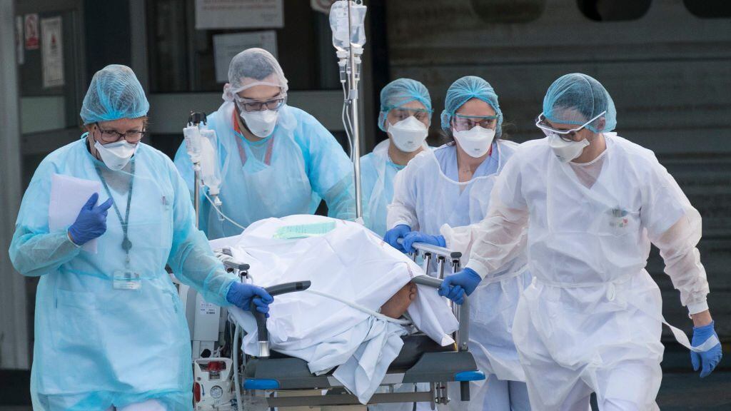 TOPSHOT - Medical staff push a patient on a gurney to a waiting medical helicopter at the Emile Muller hospital in Mulhouse, eastern France, to be evacuated on another hospital on March 17, 2020, amid the outbreak of the new Coronavirus, COVID-19. - A strict lock down requiring most people in France to remain at home came into effect at midday on March 17, 2020, prohibiting all but essential outings in a bid to curb the coronavirus spread. The country has reported 148 deaths from the virus, a number that health experts warn could soar in the coming days, seriously straining the hospital system. (Photo by SEBASTIEN BOZON / AFP) (Photo by SEBASTIEN BOZON/AFP via Getty Images)