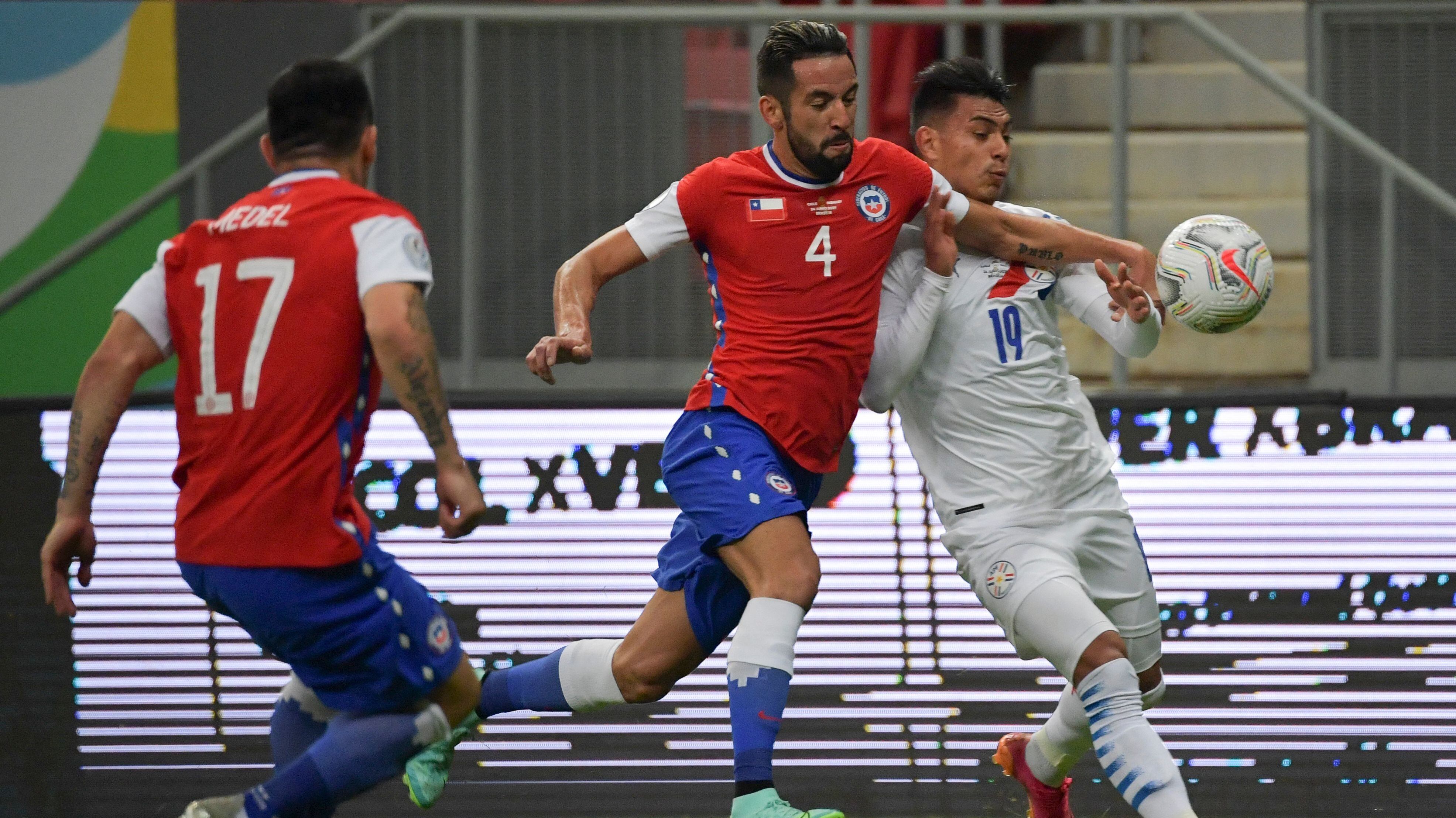 Chile's Mauricio Isla (C) and Paraguay's Santiago Arzamendia vie for the ball during their Conmebol Copa America 2021 football tournament group phase match at the Mane Garrincha Stadium in Brasilia, on June 24, 2021. (Photo by NELSON ALMEIDA / AFP) (Photo by NELSON ALMEIDA/AFP via Getty Images)