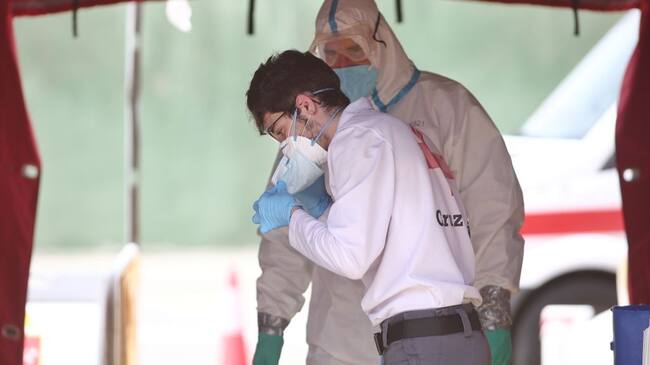 MADRID, SPAIN - MAY 05: A firefighter from the Community of Madrid is seen helping a health worker at Coslada fire station on May 05, 2020 in Madrid, Spain. Coslada fire station, which is an ambulance decontamination point and the only one operational after the closure of the campaign hospital at IFEMA fair. (Photo by Eduardo Parra/Europa Press via Getty Images)