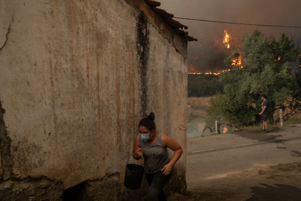Una mujer lleva agua para combatir el fuego en la zona de Busturenga de la región de Aveiro en Portugal