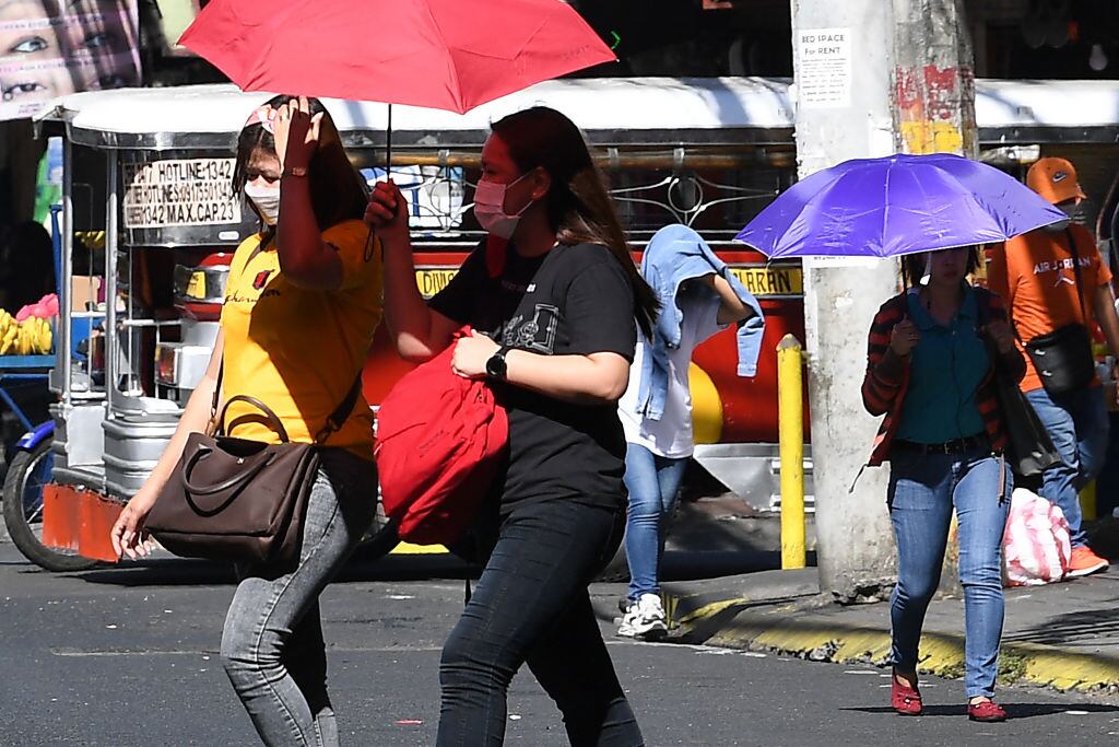 Las personas caminan con sombrillas por las calles de Manila, ante la fuerte ola de calor que se registra en Filipinas.