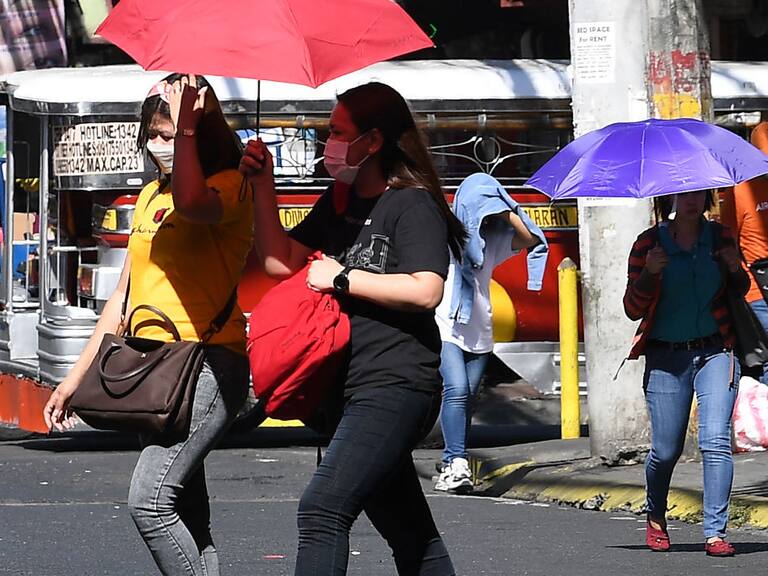 Las personas caminan con sombrillas por las calles de Manila, ante la fuerte ola de calor que se registra en Filipinas.