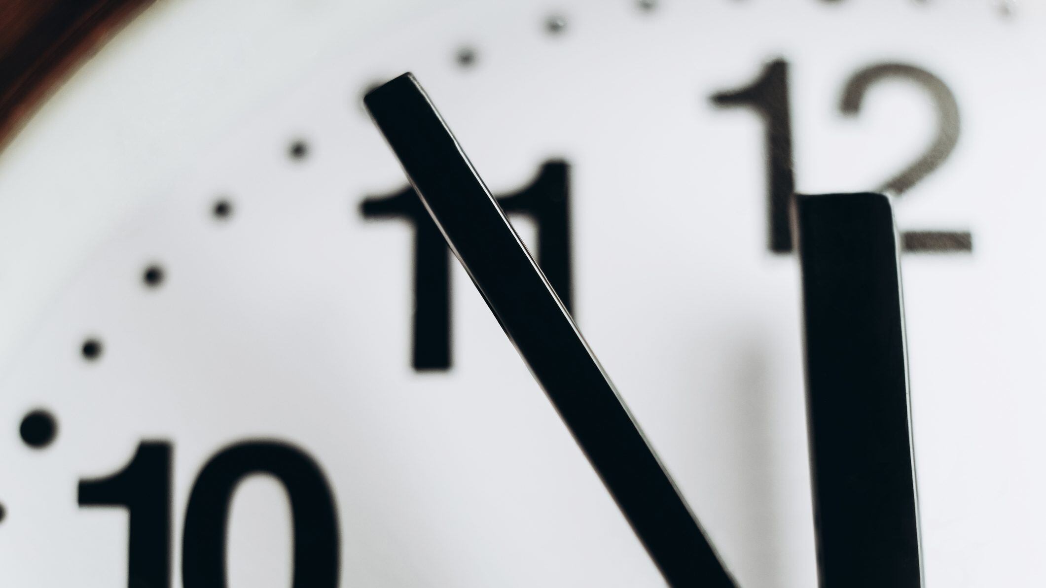 Low angle macro view of round wall clock showing 11:55.