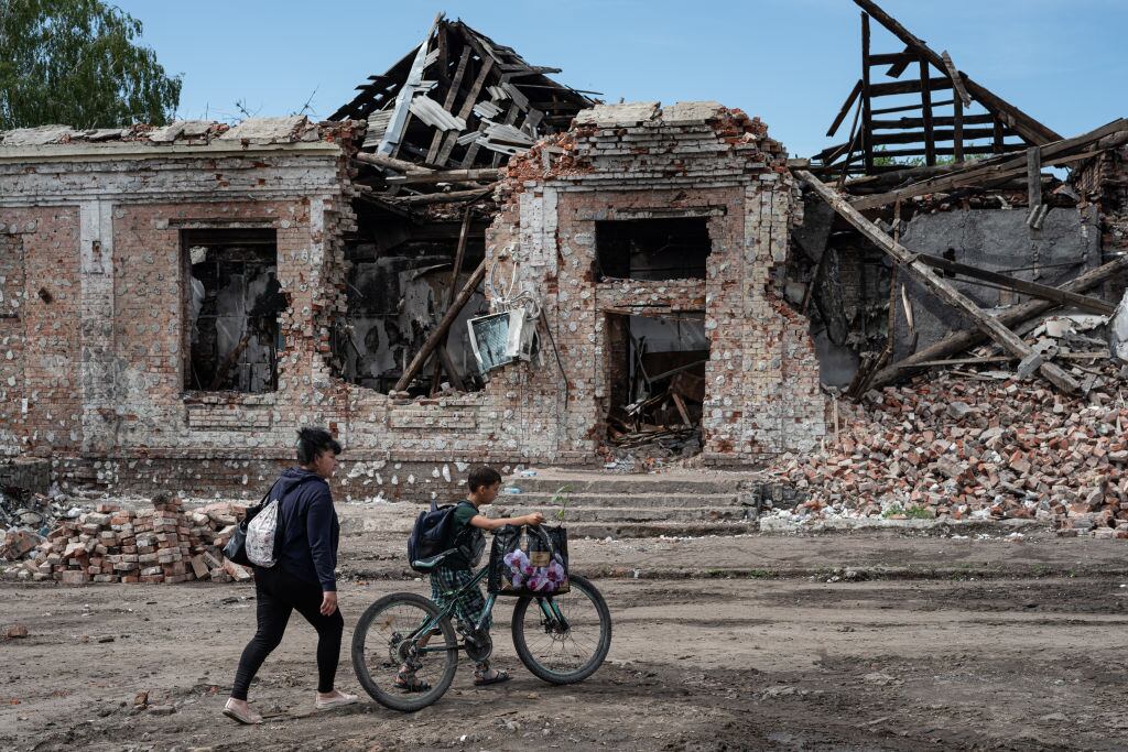 Las personas caminan ante la destrucción que deja la guerra en Trostyanets