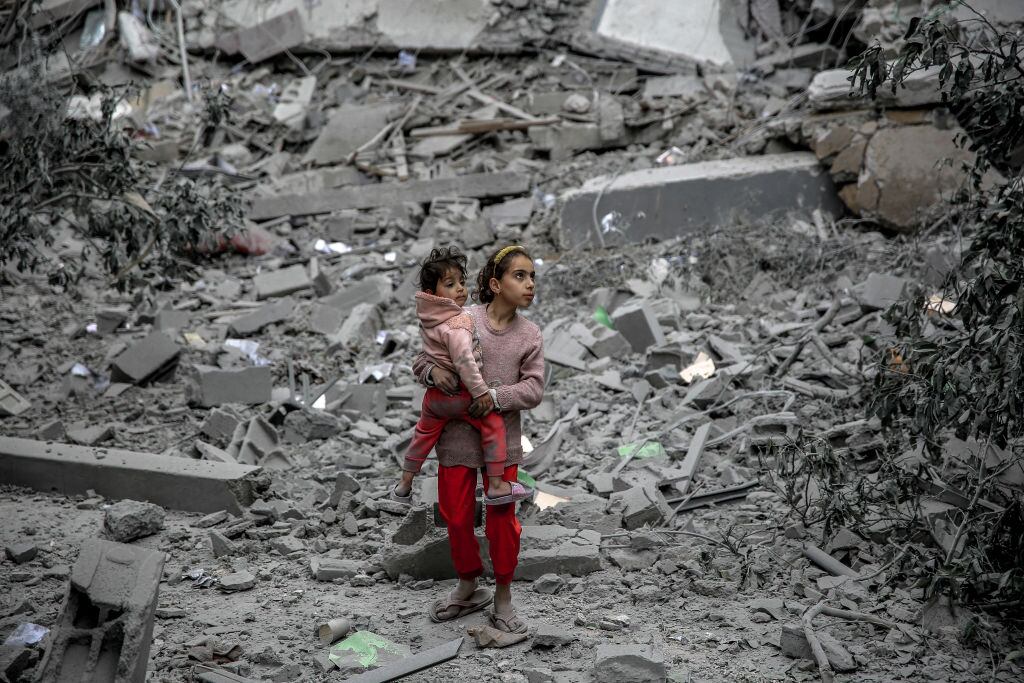 Dos niñas palestinas avanzan entre los escombros que dejan los ataques aéreos de Israel contra la Franja de Gaza en Palestina.
