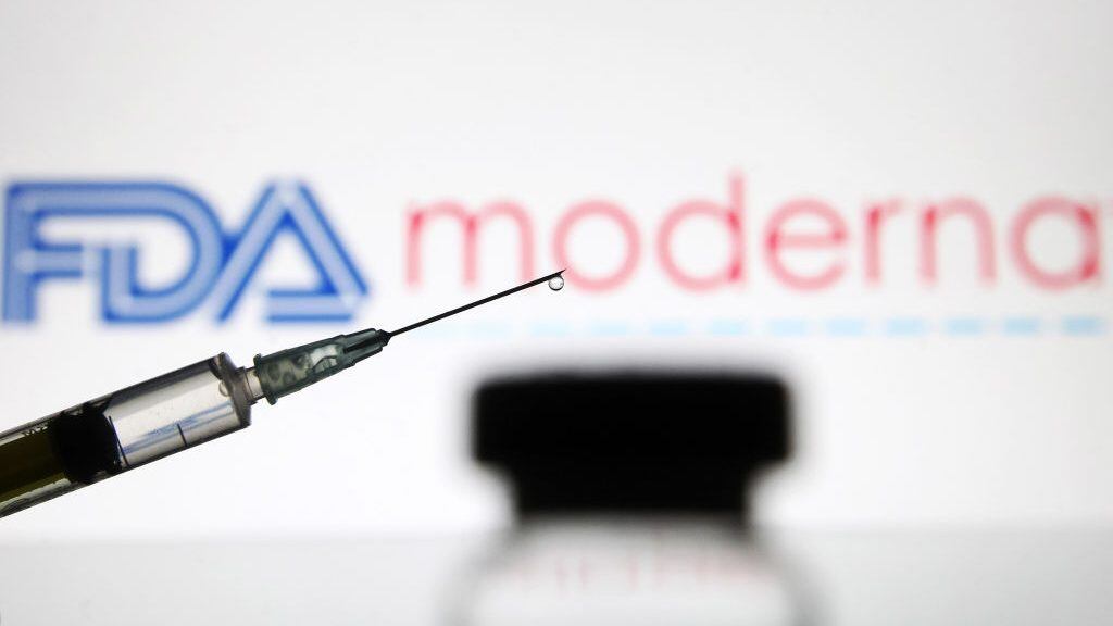 UKRAINE - 2020/12/15: In this photo illustration, a vial and a medical syringe seen displayed in front of the Food and Drug Administration (FDA) of the United States and Moderna biotechnology company's logos. FDA finds the COVID-19 vaccine. (Photo Illustration by Pavlo Gonchar/SOPA Images/LightRocket via Getty Images)