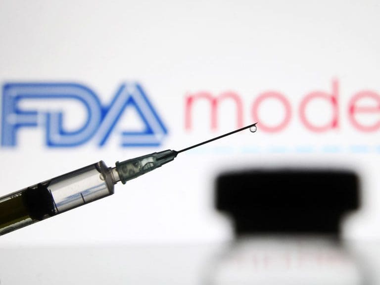 UKRAINE - 2020/12/15: In this photo illustration, a vial and a medical syringe seen displayed in front of the Food and Drug Administration (FDA) of the United States and Moderna biotechnology company&#039;s logos. FDA finds the COVID-19 vaccine. (Photo Illustration by Pavlo Gonchar/SOPA Images/LightRocket via Getty Images)