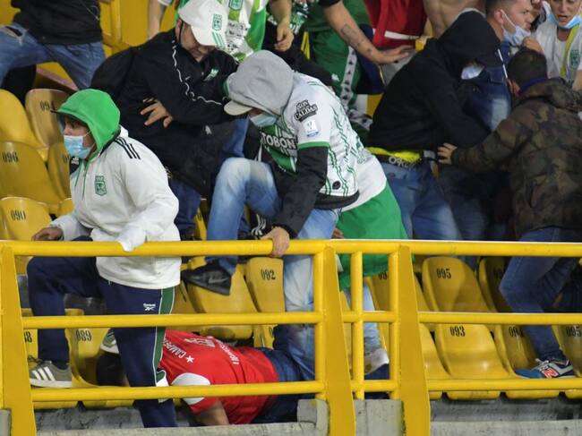 Fanáticos de Atlético Nacional patean en el suelo a un hincha del rival
