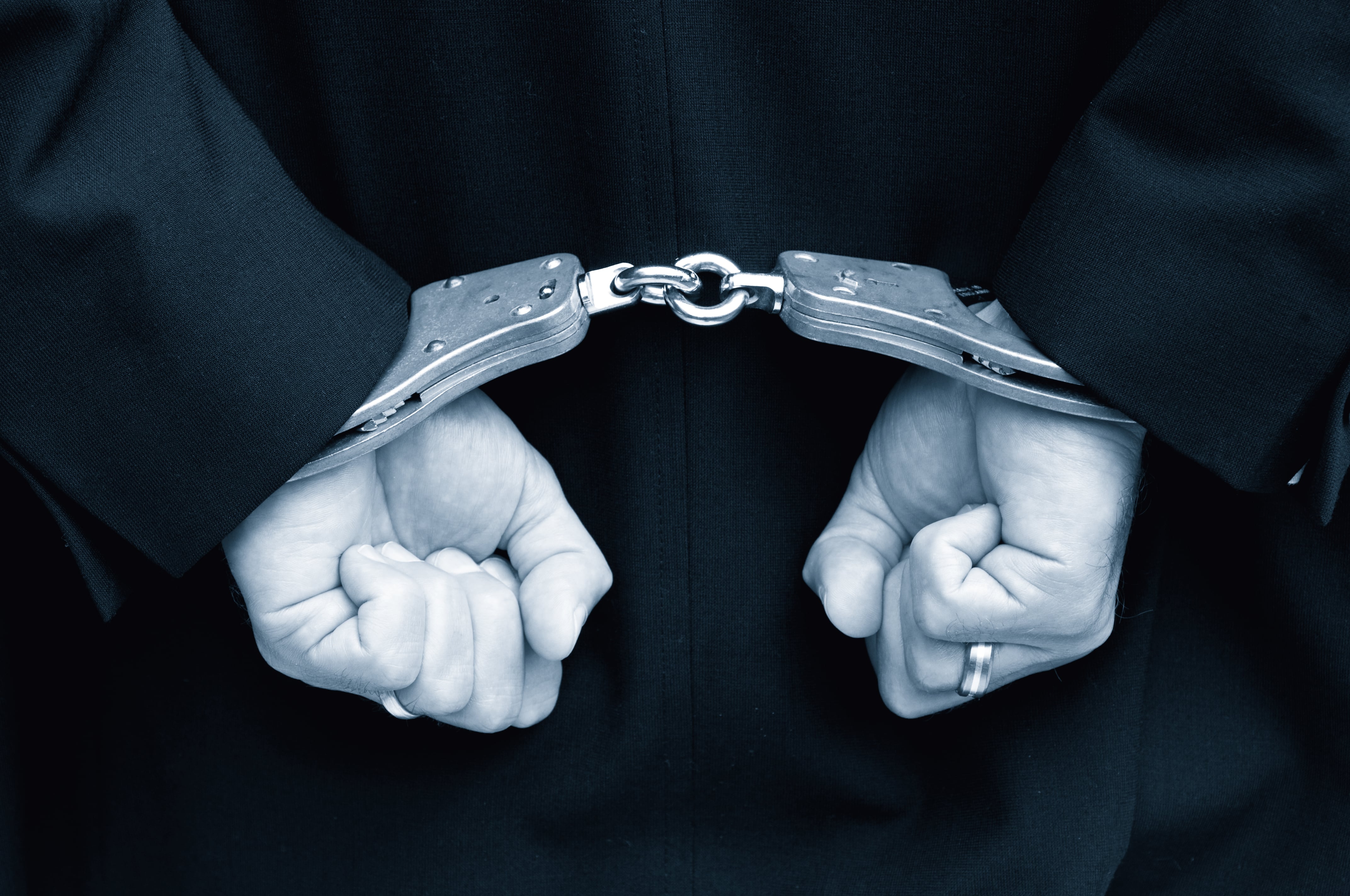 Person with hands behind back in handcuffs.