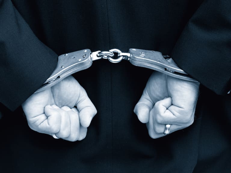 Person with hands behind back in handcuffs.