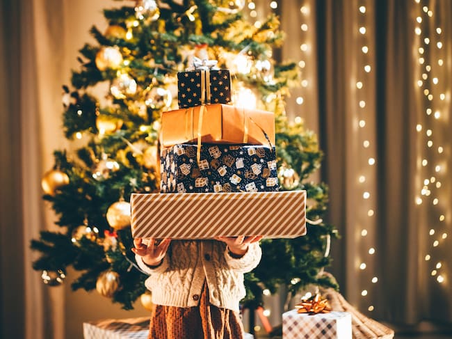Girl holding stack of Christmas presents.