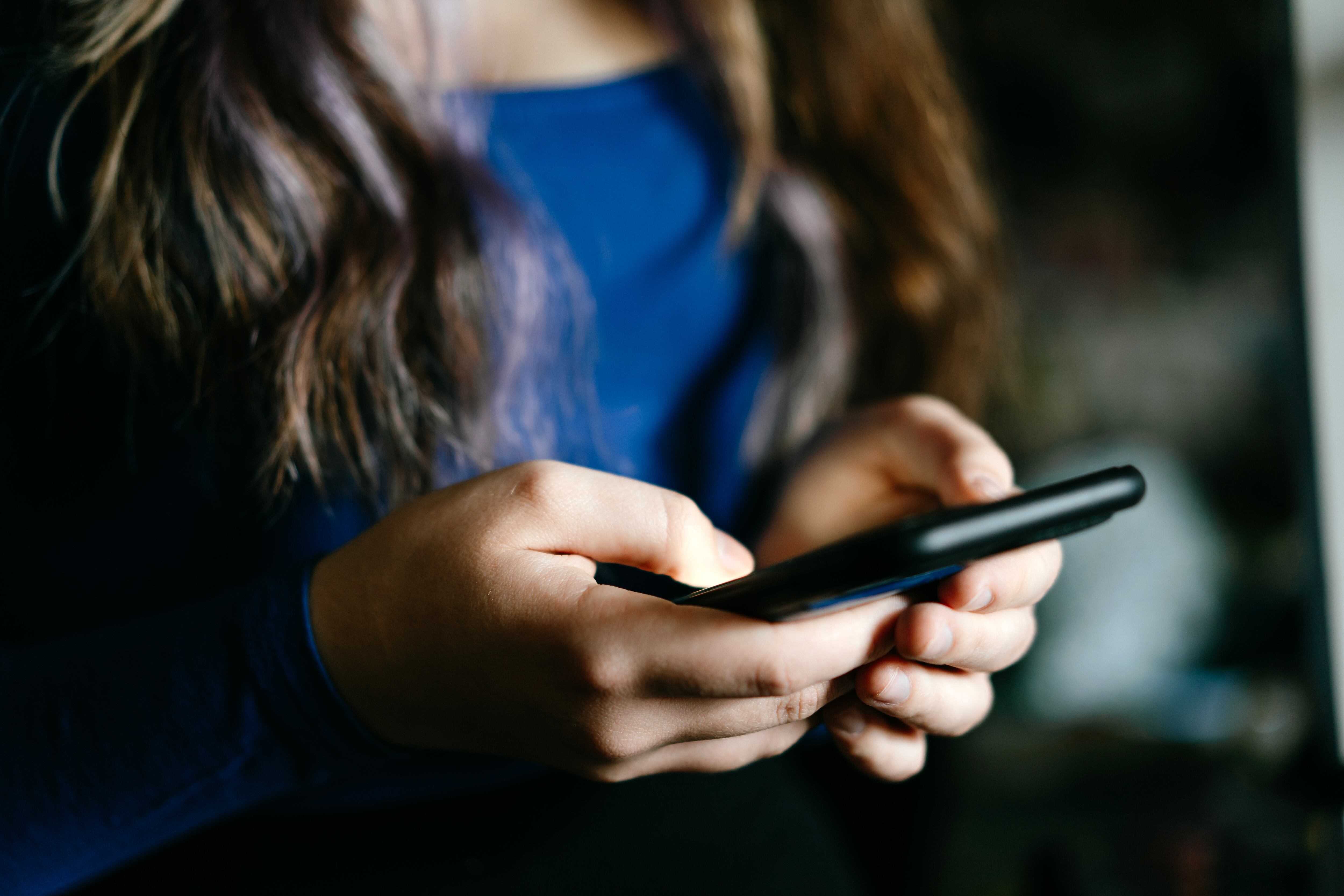 A focused view of individual's hands using a mobile phone.