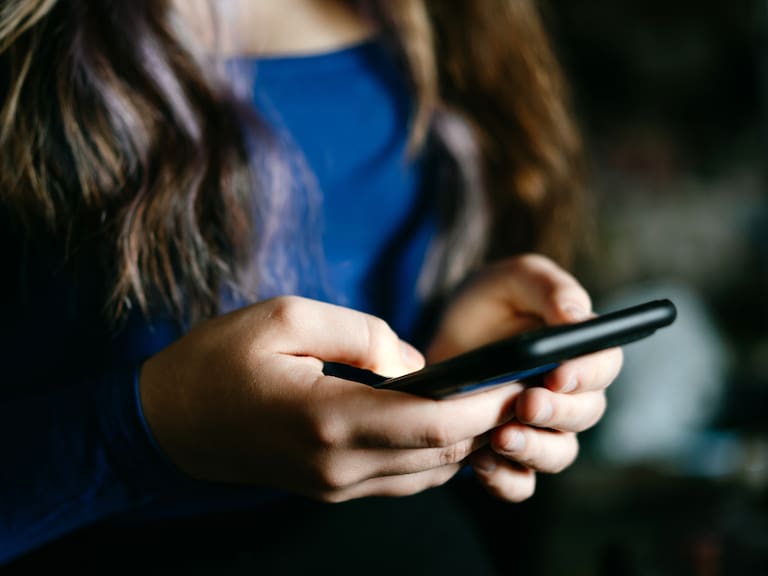A focused view of individual's hands using a mobile phone.