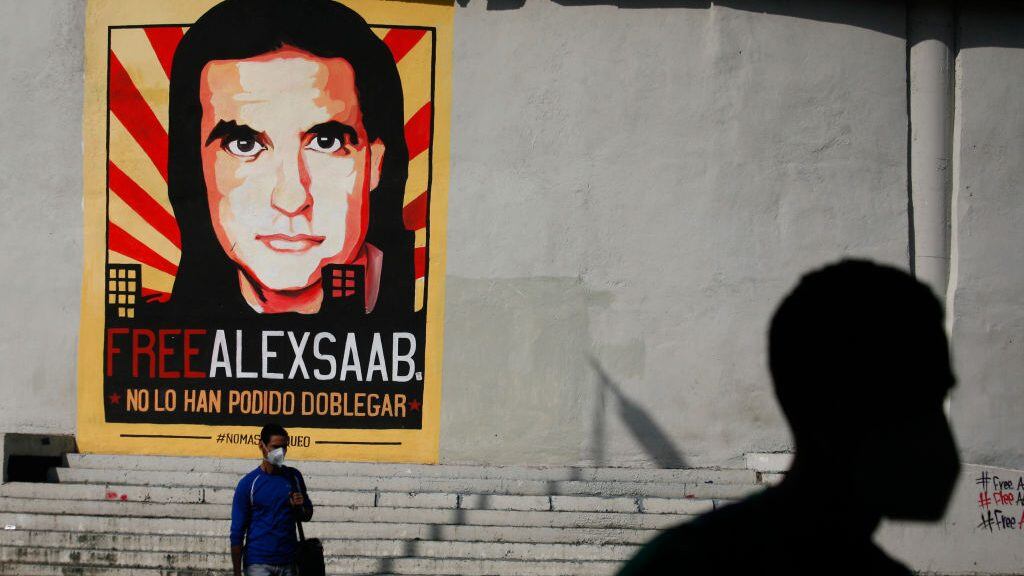 People walk past graffiti in favor of the release of Colombian businessman Alex Saab, amidst the Coronavirus pandemic, on the west side of the city in Caracas, Venezuela on September 8, 2021. (Photo by Javier Campos/NurPhoto via Getty Images)