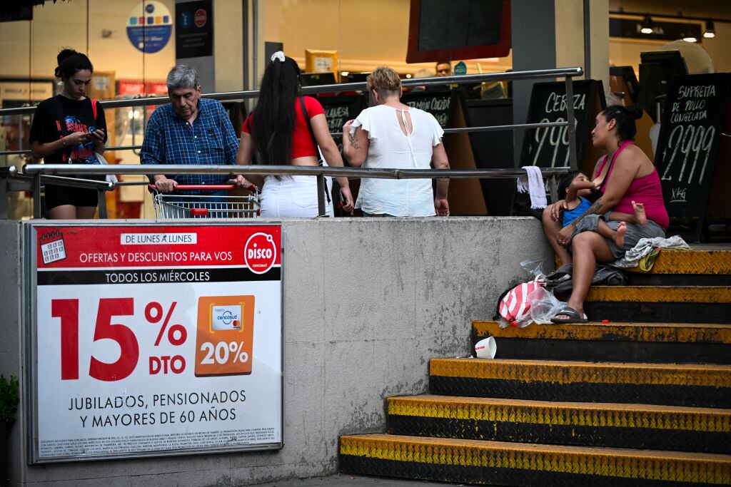 Una mujer con un bebé piden dinero a un costado de un centro comercial en la ciudad de Buenos Aires en Argentina.