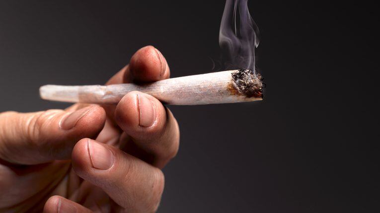 dirty fingernails and hands of drug addict holding lit marijuana joint