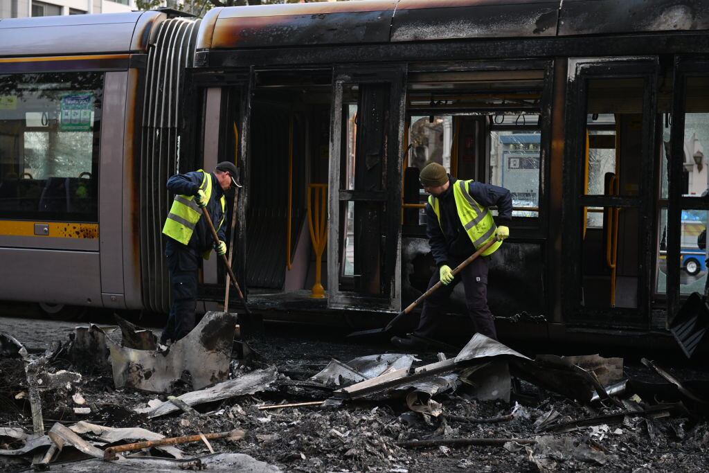 Trabajadores limpian carro de tren quemado en protestas en Dublín de Irlanda