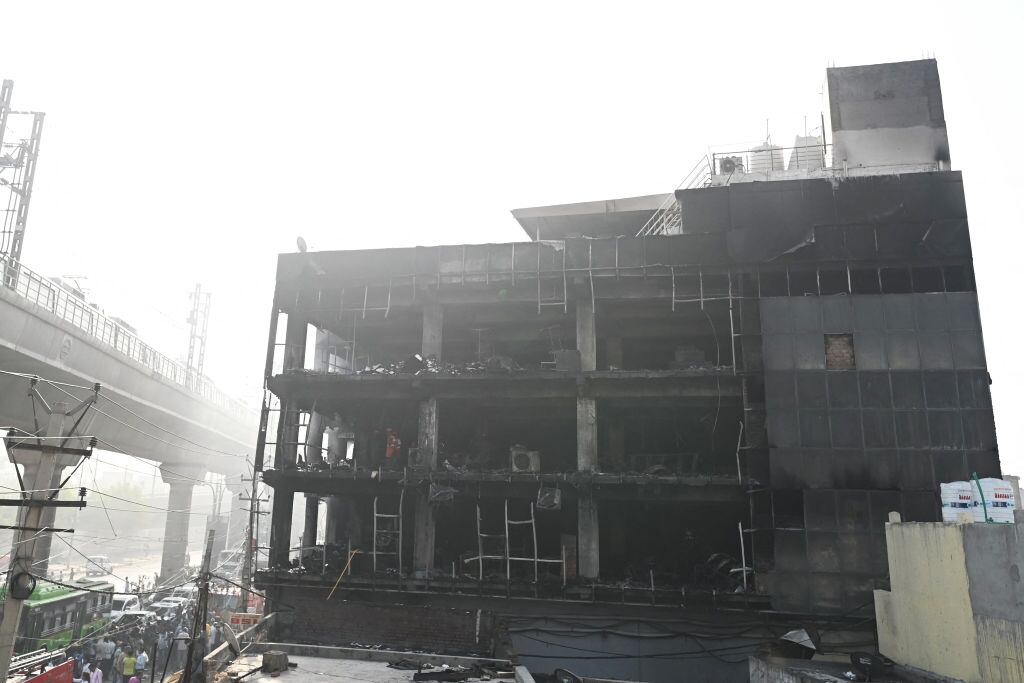 Personas observan los daños que deja el incendio de un hospital en India