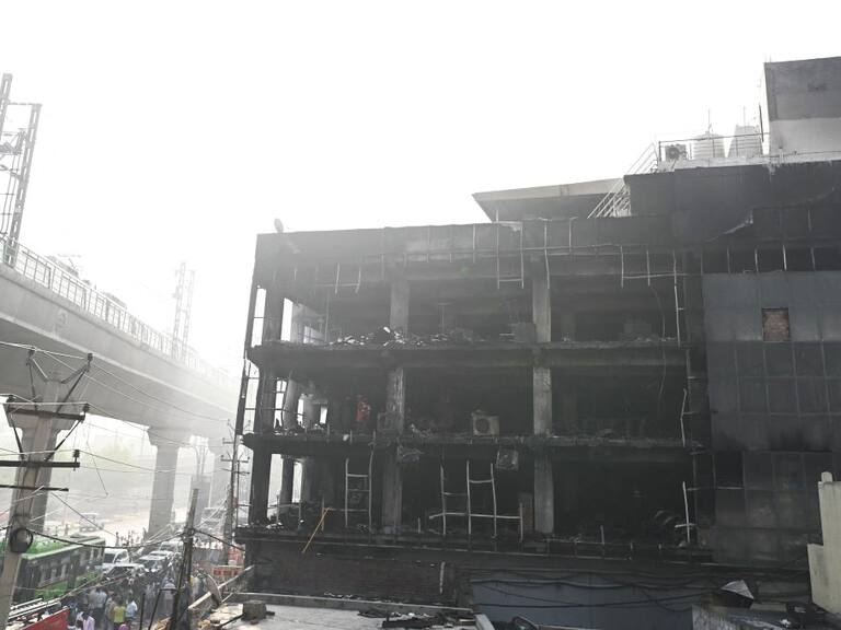 Personas observan los daños que deja el incendio de un hospital en India