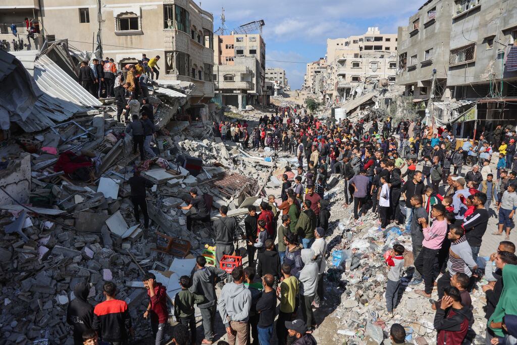 Las personas buscan entre los escombros luego del ataque de Israel contra un edificio residencial sobre la Franja de Gaza en Palestina