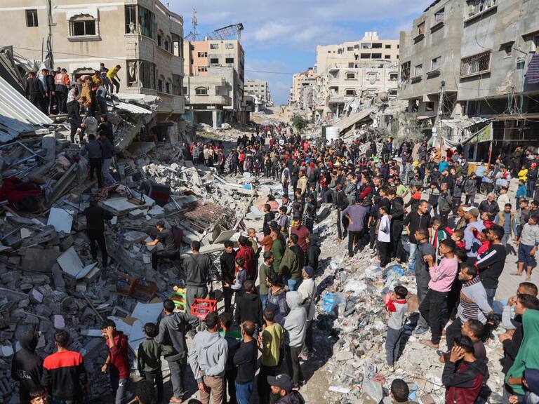 Las personas buscan entre los escombros luego del ataque de Israel contra un edificio residencial sobre la Franja de Gaza en Palestina