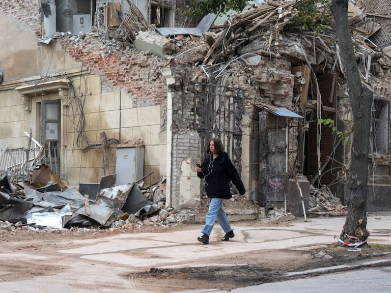 Mujer camine ante edificio destruido por misiles en Járkov en Ucrania