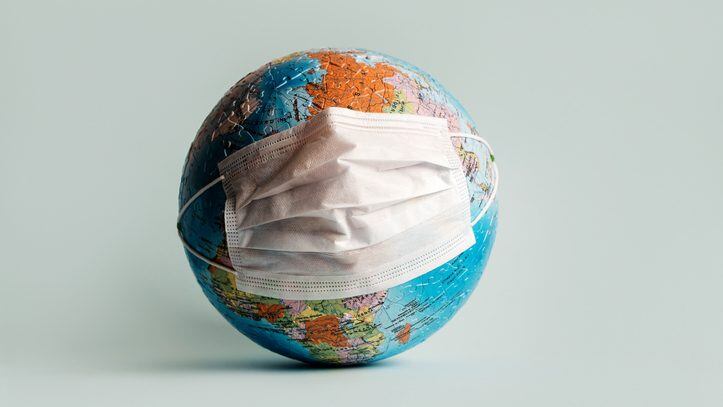 Globe made of jigsaw puzzles with a protective medical mask as a prophylaxis in the fight against coronavirus infection. Measures against the spread of the virus