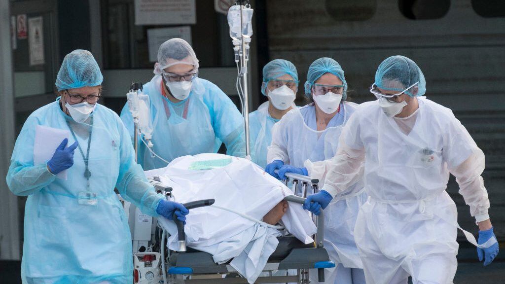 TOPSHOT - Medical staff push a patient on a gurney to a waiting medical helicopter at the Emile Muller hospital in Mulhouse, eastern France, to be evacuated on another hospital on March 17, 2020, amid the outbreak of the new Coronavirus, COVID-19. - A strict lock down requiring most people in France to remain at home came into effect at midday on March 17, 2020, prohibiting all but essential outings in a bid to curb the coronavirus spread. The country has reported 148 deaths from the virus, a number that health experts warn could soar in the coming days, seriously straining the hospital system. (Photo by SEBASTIEN BOZON / AFP) (Photo by SEBASTIEN BOZON/AFP via Getty Images)