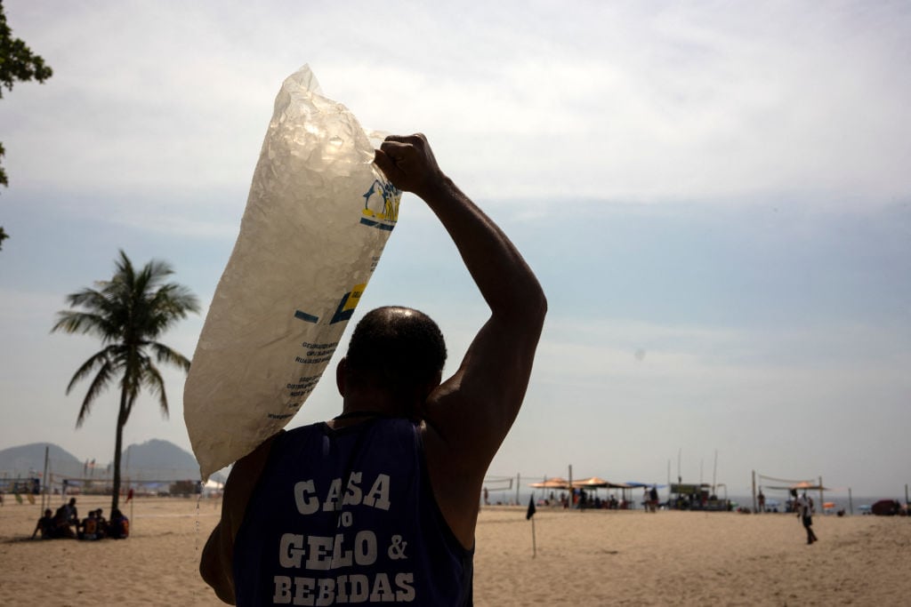 Trabajador lleva bolsa de hielo a playa de Río de Janeiro en Brasil por calor