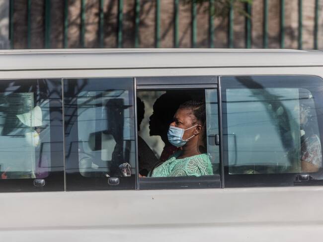 En Haití una mujer utiliza una máscara mientras es transportada en medio del brote de Covid-19
