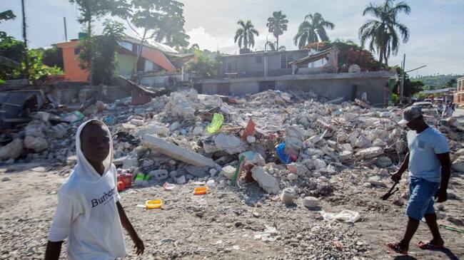 LES CAYES, HAITI - AUGUST 16: Men walk among the debris of a collapsed building after a 7.2-magnitude earthquake struck Haiti on August 16, 2021 in Corvalion, Les Cayes, Haiti. Rescue workers have been working among destroyed homes since the quake struck on Saturday and so far there are 1,297 dead and 5.700 wounded. The epicenter was located about 100 miles west of the capital city Port-au-Prince. (Photo by Richard Pierrin/Getty Images)